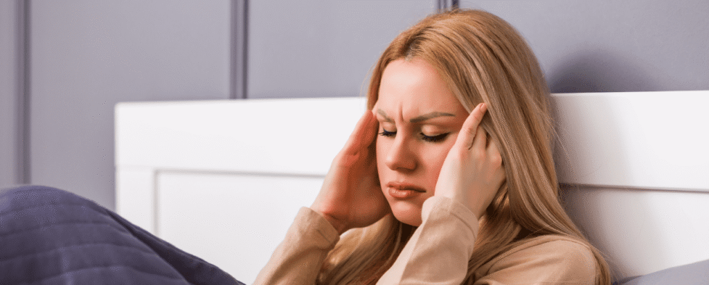 Lady sitting up in bed with a tension headache